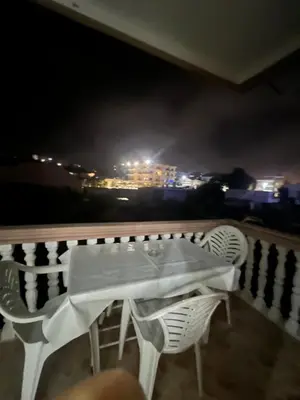 a table and chairs on a balcony at night at Keon in Ulcinj