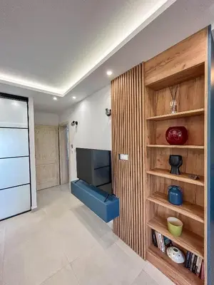 a living room with a television and wooden shelves at Sunrise Apartment in Kotor