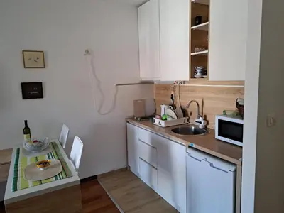 a small kitchen with a sink and a table at Petrovac Studio Apartment Ana in Petrovac na Moru