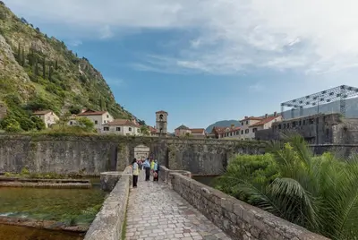 people walking over a bridge over a river at Apartman Maestral in Kotor