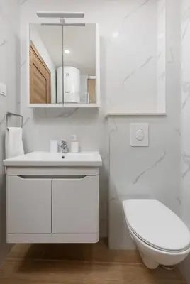 a white bathroom with a sink and a toilet at Apartman Maestral in Kotor