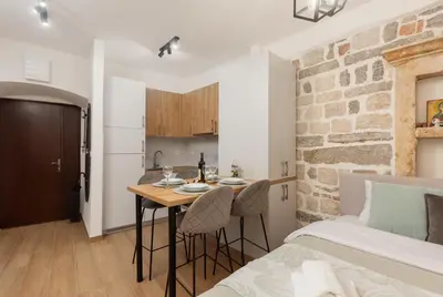 a room with a bed and a table with chairs at Apartman Maestral in Kotor