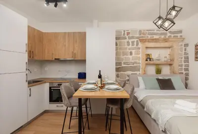 a room with a bed and a table and a kitchen at Apartman Maestral in Kotor