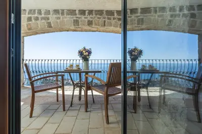 a table and chairs on a balcony with a view of the ocean at Castello degli Aranci Eco Resort in Petrovac na Moru