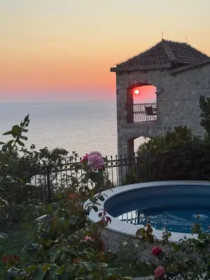 a building with a swimming pool in front of the ocean at Castello degli Aranci Eco Resort in Petrovac na Moru