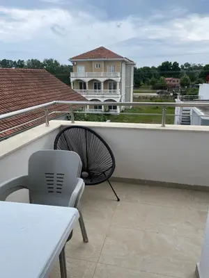 a chair and table on a balcony with a house at Villa Draga in Ulcinj