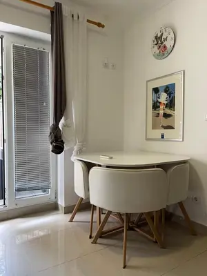 a dining room with a table and chairs and a clock at Stan Budva - Potkosljun in Budva