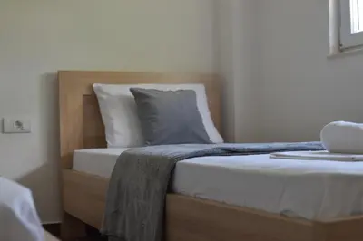 a bedroom with a bed with a wooden headboard at KenDar Family Apartments in Ulcinj