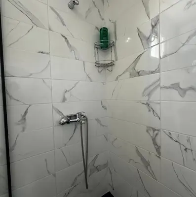 a bathroom with a shower with white marble walls at KenDar Family Apartments in Ulcinj