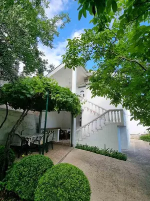 a white house with a staircase and a table and chairs at Cozy House Haj Nehaj in Sutomore