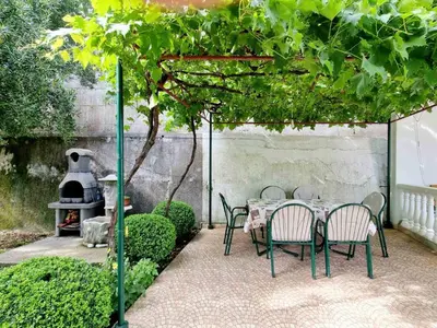 a table and chairs under a pergola in a garden at Cozy House Haj Nehaj in Sutomore