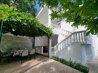 a white house with a table and chairs and stairs at Cozy House Haj Nehaj in Sutomore