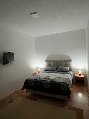 a bedroom with a bed with two lamps and a tv at Villa Bubanja with shared pool in Kotor