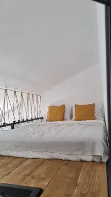 a white bedroom with a bed with two yellow pillows at Aloft Apartment in Budva