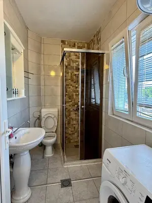a bathroom with a toilet and a sink and a washing machine at Hida Ile apartments in Ulcinj
