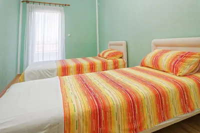 a bedroom with two beds with colorful sheets and a window at Apartments Ajla in Utjeha