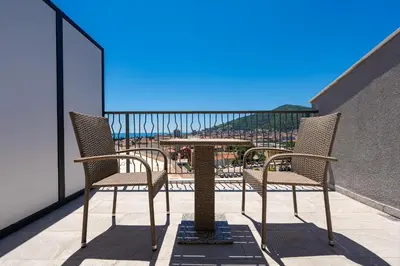 two chairs and a table on a balcony with a view at Rooftop Apartments & Rooms in Budva