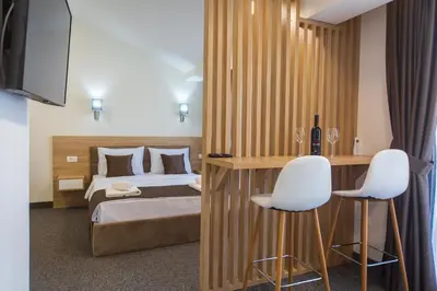 a bedroom with a bed and two white chairs at Rooftop Apartments & Rooms in Budva