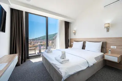 a hotel room with a bed and a large window at Rooftop Apartments & Rooms in Budva