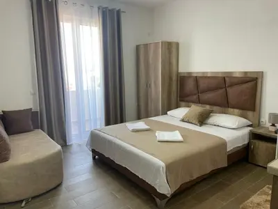 a bedroom with a large bed and a chair at Dragaj Apartments in Ulcinj