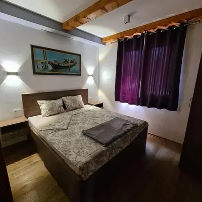 a bedroom with a bed with purple curtains at Orahovo stone vilas in Virpazar