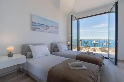 two beds in a bedroom with a view of the ocean at Villa Krstac in Budva