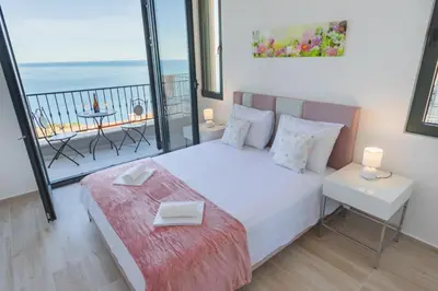 a bedroom with a bed and a balcony with the ocean at Villa Krstac in Budva