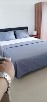a person sitting on a chair next to a bed at STANDART Premium in Ulcinj