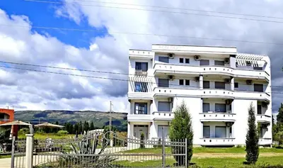 a white building with a fence in front of it at STANDART Premium in Ulcinj