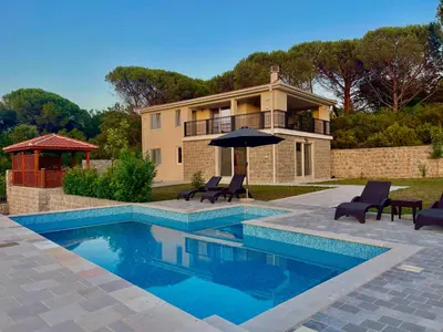 a house with a swimming pool with chairs and an umbrella at Villa Petra Zagora in Zagora