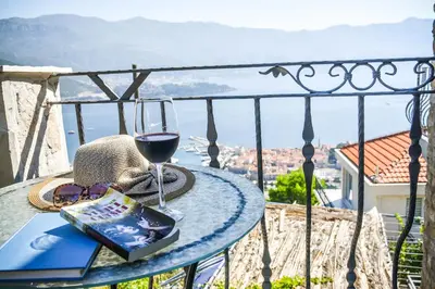 a table with a glass of wine and a book at Studios Kalina in Budva