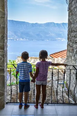 two children standing on a balcony looking out at the water at Studios Kalina in Budva