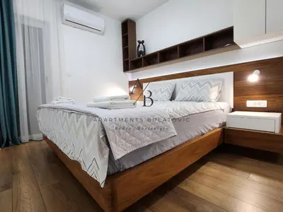 a bedroom with a large bed with a wooden headboard at Apartments Bulatovic in Budva