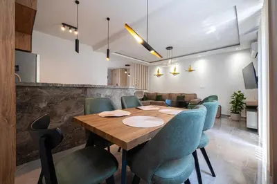 a dining room with a wooden table and blue chairs at Cosy Duplex near Bus Station in Budva