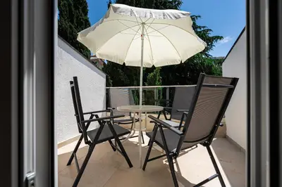 a table and chairs and an umbrella on a balcony at Cosy Duplex near Bus Station in Budva