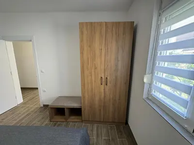 a bedroom with a wooden cabinet next to a window at Adla Apartmani in Ulcinj