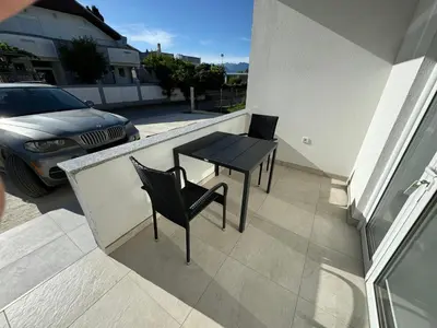 a small balcony with a black table and chairs on it at Adla Apartmani in Ulcinj