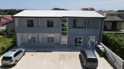 two cars parked in a parking lot in front of a house at Adla Apartmani in Ulcinj