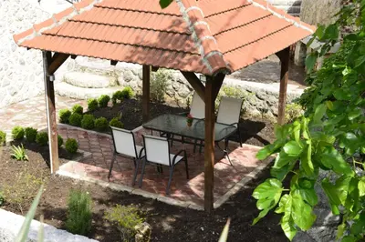 a gazebo with a table and chairs in a garden at Villa Andrea Apartments with parking in Kotor