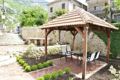 a wooden gazebo with a table and chairs at Villa Andrea Apartments with parking in Kotor