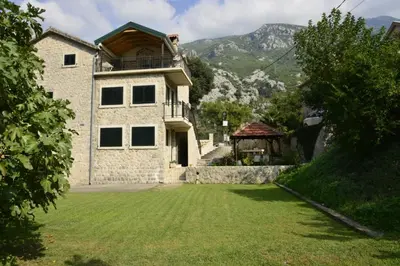 a large house with a grass yard in front of it at Villa Andrea Apartments with parking in Kotor