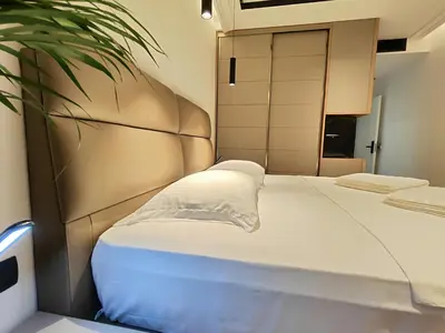 a bedroom with a white bed with a plant at AMD Premium rooms Budva in Budva
