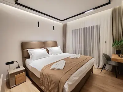 a bedroom with a large bed and a desk at AMD Premium rooms Budva in Budva