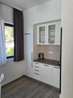 a kitchen with white cabinets and a window at Cozy studio apartment in Petrovac in Petrovac na Moru