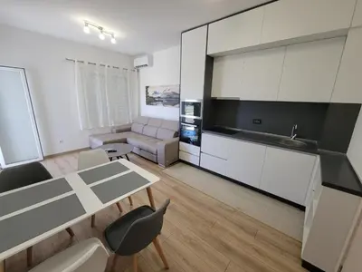 a kitchen and living room with a table and a couch at Angie's in Ulcinj