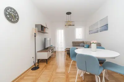 a living room with a white table and blue chairs at New Renovated Warm Cozy Fully Equipped One Bedroom Apartment in Budva, Free Parking, Ideal for Long Stays in Budva
