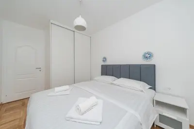 a white bedroom with a large white bed with two white towels at New Renovated Warm Cozy Fully Equipped One Bedroom Apartment in Budva, Free Parking, Ideal for Long Stays in Budva