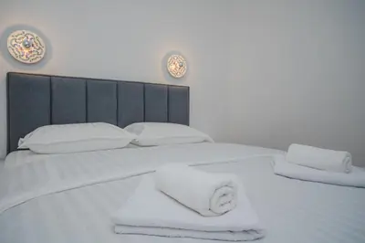 a white bed with towels on top of it at New Renovated Warm Cozy Fully Equipped One Bedroom Apartment in Budva, Free Parking, Ideal for Long Stays in Budva