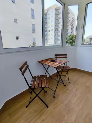 a table and two chairs in a room with windows at New Renovated Warm Cozy Fully Equipped One Bedroom Apartment in Budva, Free Parking, Ideal for Long Stays in Budva