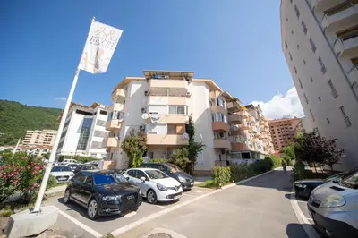 a parking lot with cars parked in front of a building at New Renovated Warm Cozy Fully Equipped One Bedroom Apartment in Budva, Free Parking, Ideal for Long Stays in Budva